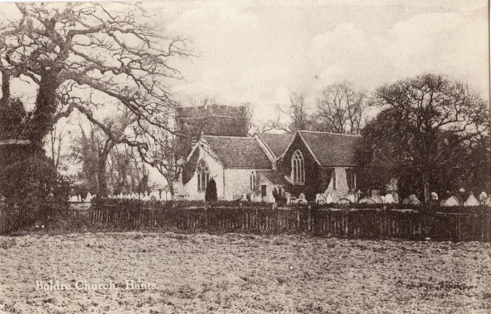 A sepia-toned photo of a historic church surrounded by trees and a graveyard, enclosed by a wooden fence. The text “Boldre Church, Hants.” is visible in the bottom left corner.
