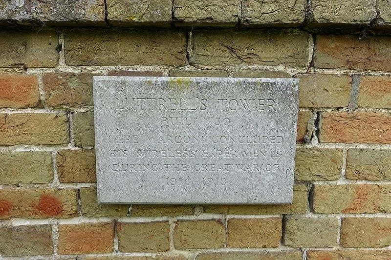 A stone plaque on a brick wall reads: Luttrells Tower Built 1780. Here Marconi concluded his wireless experiments during the Great War of 1914-1918.