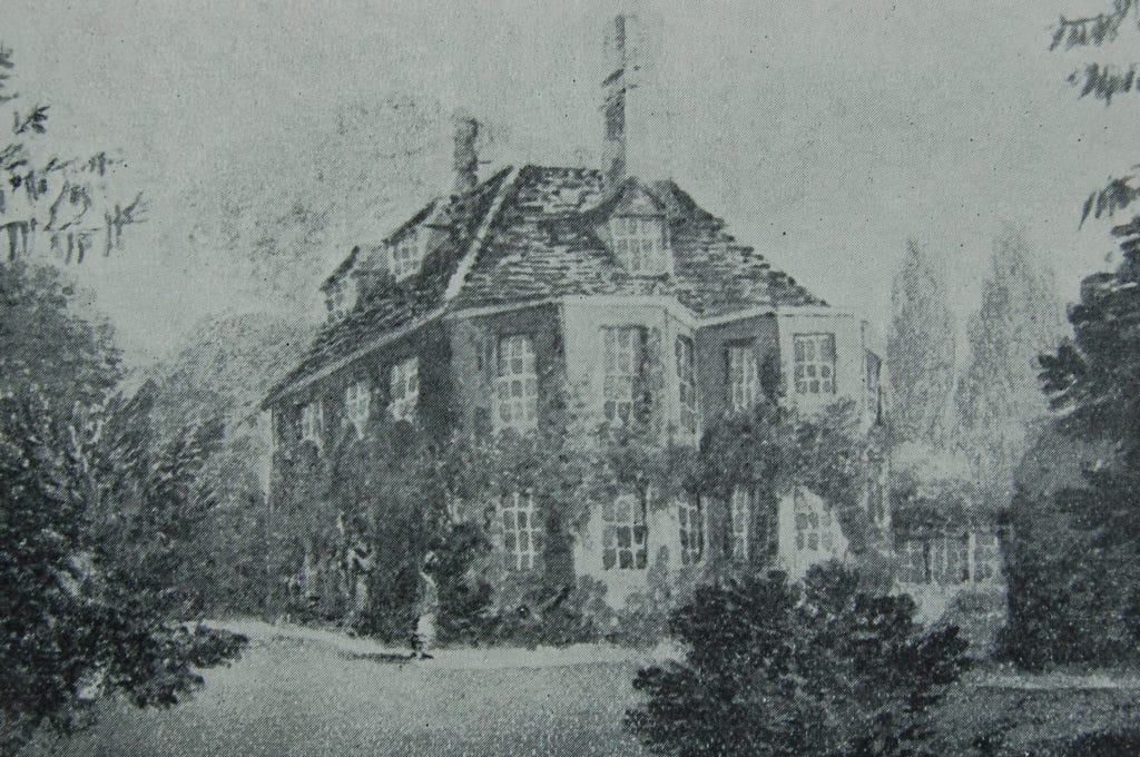 A black and white drawing of a large, two-storey house with tall chimneys, many windows, and leafy trees surrounding it. The house appears old-fashioned and is partly covered by climbing plants.